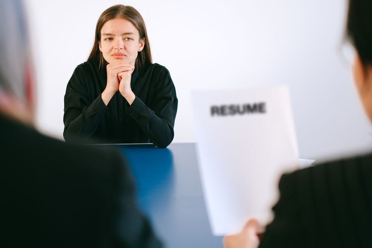 Home A woman in a job interview facing two employers with a focus on her resume.