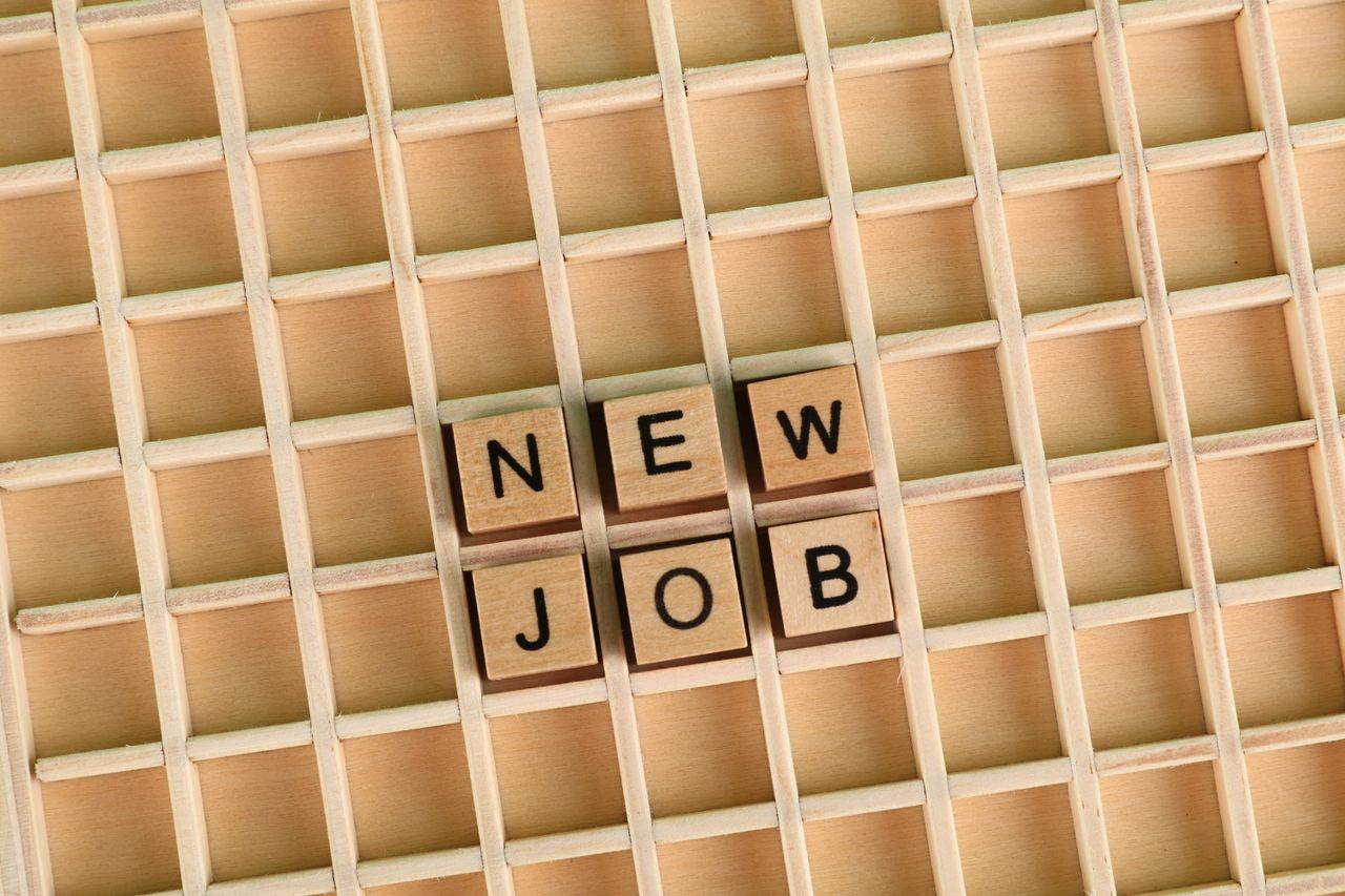 Discover the excitement of a new job with wooden letter tiles spelling 'NEW JOB' on a grid.